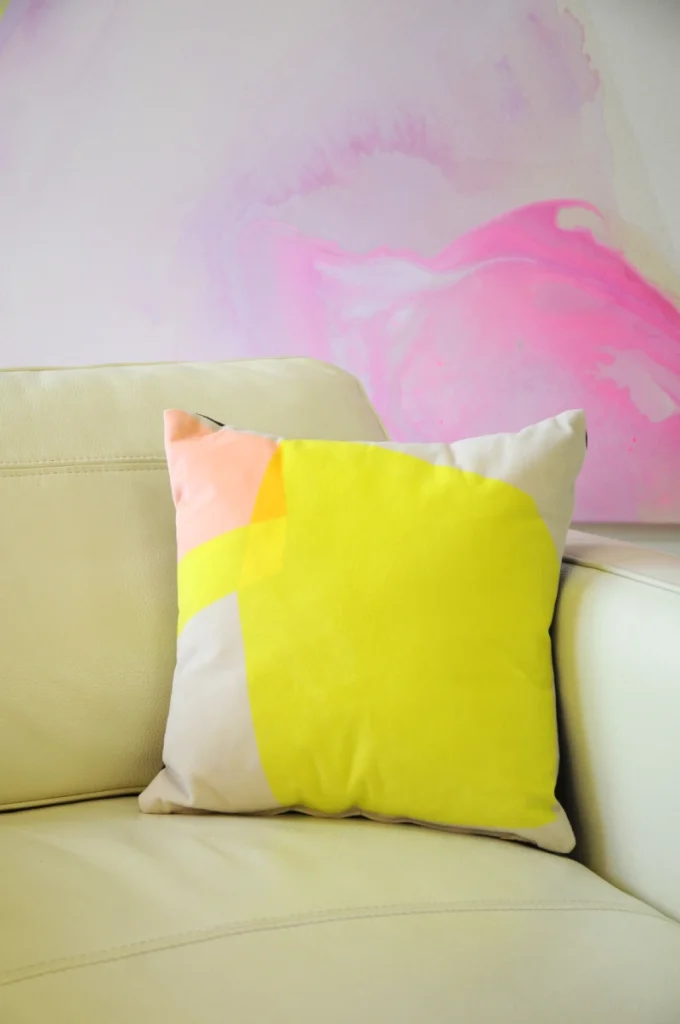 sustainable velvet cushion on a cream chair with a painting on the wall behind it